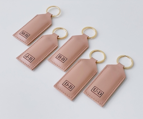 Kit de chaveiros personalizado com cinco unidades em couro rose, com argola dourada e iniciais gravadas em cada peça, ideal para presentear.