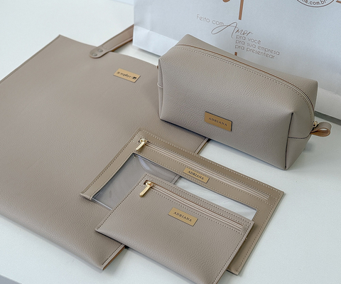 Kit com bolsa e três necessaires de couro sintético personalizado, acompanhado de sacola para presente, ideal para organização e presentes corporativos.