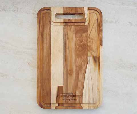 Tábua para churrasco em madeira teca personalizada, retangular, com alça e acabamento natural, ideal para cortar e servir carnes.