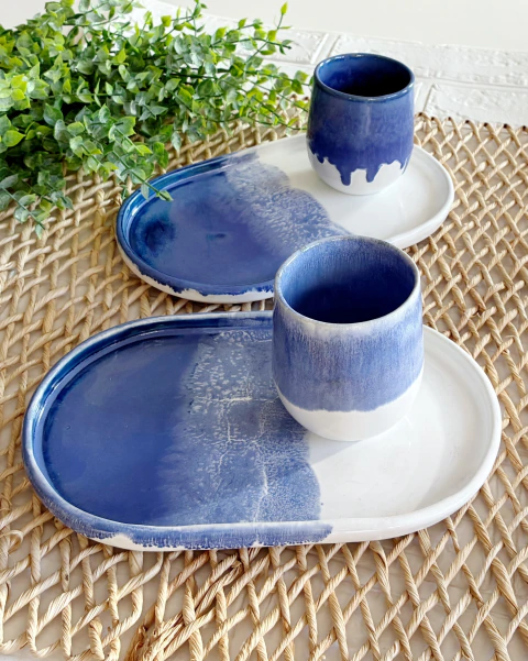 Conjunto de prato e copo em cerâmica com acabamento azul degradê sobre fundo branco. Feito em cerâmica artesanal. Próprio para uso com alimentos.