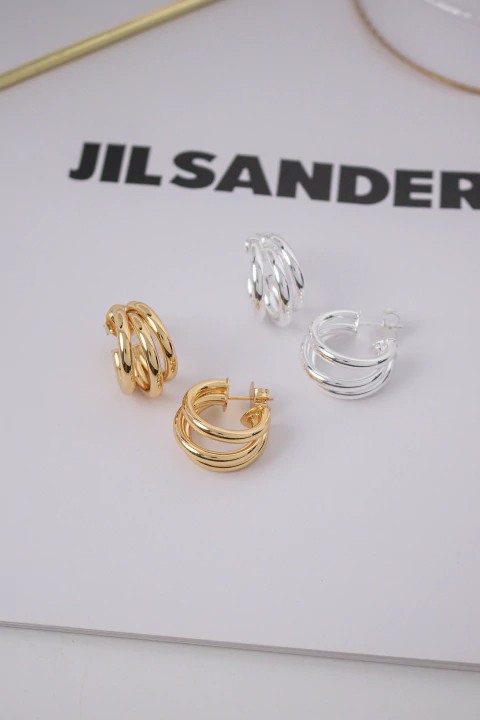 Brinco argola com 3 hastes na cor dourada e prata sobre superficie branca