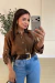 Cinto Dakota marrom com fivela dourada em destaque, usado por mulher com camisa marrom e calça jeans, em ambiente interno.