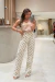 Mulher usando a Calça Yandra de poá branca com preto, calça de moda feminina com modelagem reta, em ambiente de loja moderna.