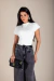 Mulher vestindo body branco manga japonesa com calça jeans escura e segurando bolsa preta
