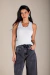 Mulher usando blusa regata branca com detalhes em renda e laço pequeno na gola, combinada com calça jeans preta de cintura alta