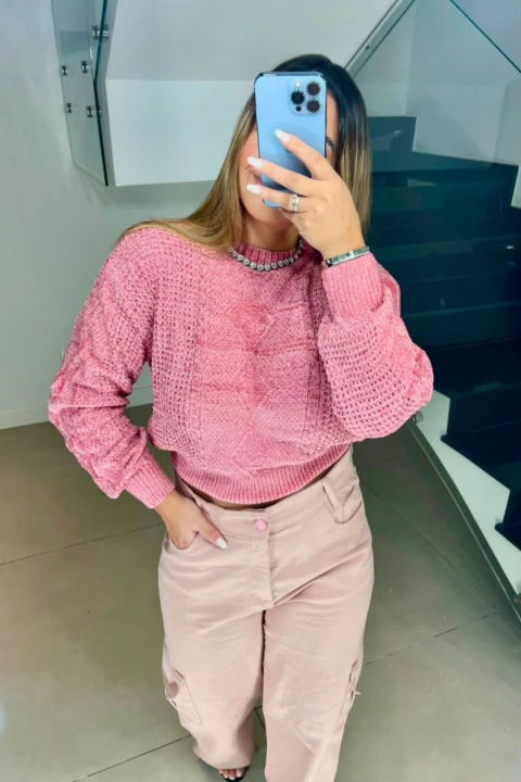 Mulher usando blusa fio mousse curta rosa com calça bege clara em ambiente interno