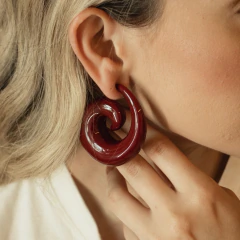 Brinco espiral vermelho feito de resina usado em orelha feminina