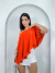 Mulher vestindo blusa bata assimétrica laranja com um ombro à mostra
