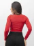 Mulher usando body vermelho com decote torcido e mangas longas. 