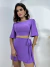 Mulher vestindo conjunto lilás Duna Madri com blusa cropped de mangas curtas e saia curta com amarração lateral