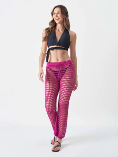 Mulher usando calça tricô fúcsia transparente como saída de praia