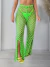 Mulher vestindo calça saída de praia verde limão com fenda frontal e estampa de crochê
