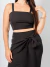Mulher usando conjunto alfaiataria Lara preto com cropped de alças e saia midi com amarração frontal