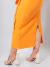 Mulher usando conjunto alfaiataria Lara laranja com cropped de alças e saia midi com amarração frontal