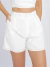 Mulher vestindo conjunto linho branco com top cropped de alças finas e shorts de cintura alta