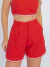 Mulher vestindo conjunto linho vermelho com top cropped de alças finas e shorts de cintura alta
