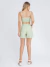 Mulher vestindo conjunto linho verde-menta com top cropped de alças finas e shorts de cintura alta