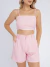Mulher vestindo conjunto linho rosa com top cropped de alças finas e shorts de cintura alta