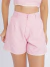 Mulher vestindo conjunto linho rosa com top cropped de alças finas e shorts de cintura alta