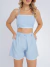 Mulher vestindo conjunto linho azul-claro com top cropped de alças finas e shorts de cintura alta