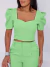 Mulher usando conjunto feminino verde-claro com blusa de mangas bufantes e calça ajustada