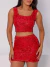 Mulher vestindo conjunto paetê vermelho composto por cropped e saia curta