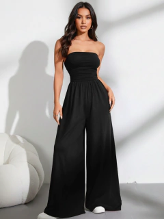 Mulher vestindo macacão drapeado preto com pantalona larga e tomara que caia