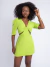 Macaquinho Ste manga curta na cor verde lima vibrante com recortes na cintura e decote em V com nó frontal