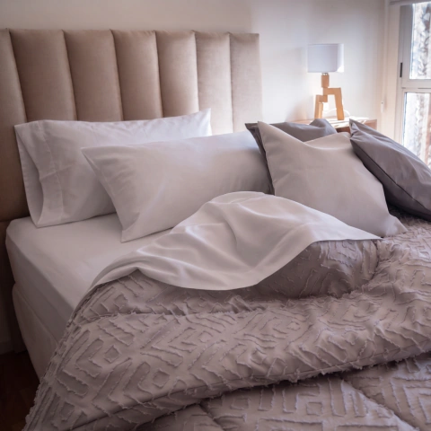 Juego de sábanas hoteleras percal 180 hilos en cama con almohadones blancos y beige