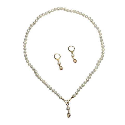 Conjunto de colar e brincos de pérolas ovais e cristais em fundo branco.