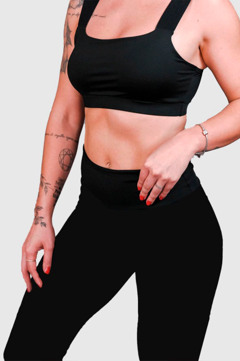 Mulher usando legging NC Extreme preta com fita refletiva e top esportivo preto, destacando conforto e estilo para atividades físicas