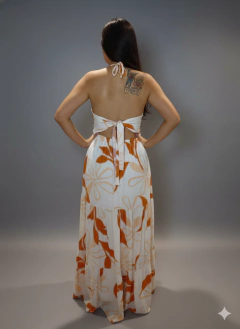 Mulher vestindo vestido longo branco com estampa floral laranja e alças cruzadas no pescoço