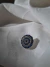 Escarapela circular con piedras azules y blancas sobre tela blanca