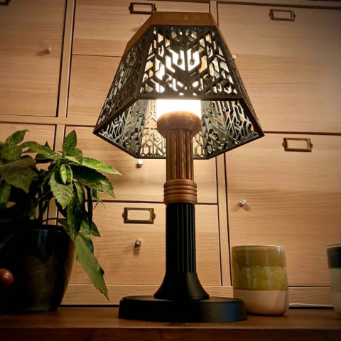 Cúpula luminária de mesa estilo Art Déco acesa sobre um móvel de madeira ao lado de uma planta, projetando uma luz difusa e acolhedora.