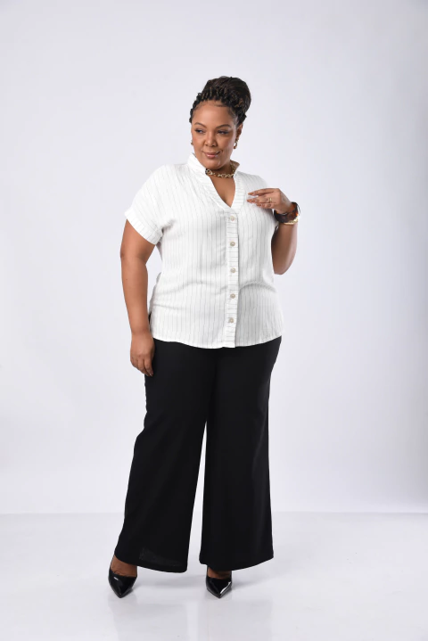 Mulher usando pantalona preta de linho viscose com camisa branca de botões e sapatos pretos de salto