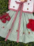Vestido infantil com estampa listrada verde e branca, detalhes em vermelho com bordados de morangos, acompanhado de sapatinhos vermelhos e meias vermelhas com babados.