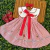 Vestido infantil vermelho e branco com listras, gola branca bordada com desenhos de cogumelos, laço vermelho frontal, acompanhado de laço de cabelo e sapatinhos vermelhos
