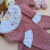 Conjunto saída maternidade rosa em tricô com padronagem de losangos, macacão com detalhes em tecido branco e renda, acompanhado de manta rosa e sapatinhos de tricô com bordado floral