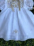 Vestido branco clássico para bebê com aplicação de renda renascença artesanal no peitilho, laço de cetim bege na gola e bordados delicados na saia