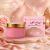 Creme hidratante concentrado Sabah Al Ward Sugar em pote rosa com tampa dourada ao lado de caixa rosa decorada, sobre base dourada com flores e tecido rosa ao fundo
