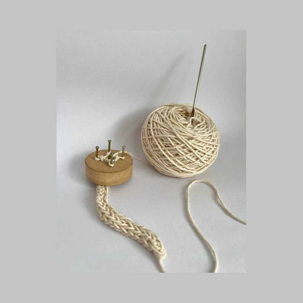 Telar para cordón de cuatro clavos con un cordón tejido en hilado crudo
