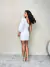 Modelo usando um vestido branco de manga balonê com detalhe de nó na frente e recorte lateral.