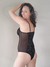Mujer posando de espaldas con un body negro de terciopelo y transparencia, sonriendo y mostrando una actitud relajada.