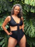 Modelo luciendo el corpiño Claire, un traje de baño negro con un diseño elegante y moderno, rodeado de hojas verdes.