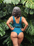 Modelo de traje de baño colaless verde, vista posterior entre hojas tropicales.