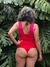 Corpiño de bikini en colores rojo y fucsia, visto desde atrás, rodeado de hojas verdes.