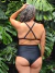 Vista trasera de un corpiño negro con breteles cruzados, combinado con un bikini de tiro alto, en un entorno natural con hojas verdes.