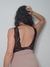 Vista trasera de un body nude con puntilla negra, modelado por una mujer con cabello rizado.