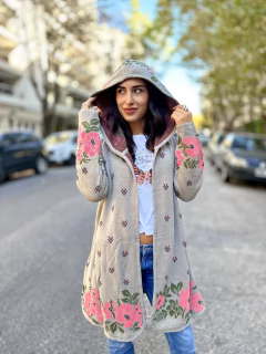 Saco tipo sacón color gris claro con capucha y diseño floral en tonos rosas y verdes, usado por una mujer joven en la calle