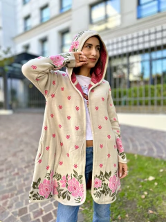 Sacón beige con capucha y diseño floral en tonos rosas y verdes, con bolsillos laterales, usado por una mujer joven en un entorno urbano